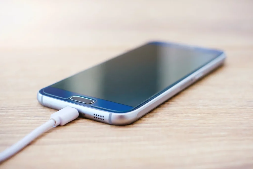 Smartphone sur un bureau en bois clair et sa batterie en charge
