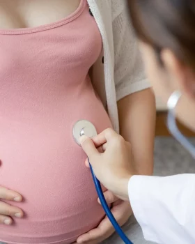 Femme enceinte en train de se faire ausculter par une femme pédiatre