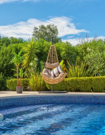 Villa de luxe avec fauteuil en osier suspendu au bord de la piscine
